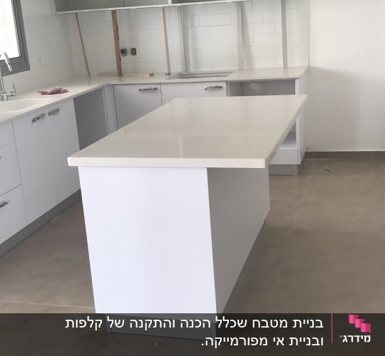 מטבח חדש עם ארונות לבנים ומשטח עבודה גדול